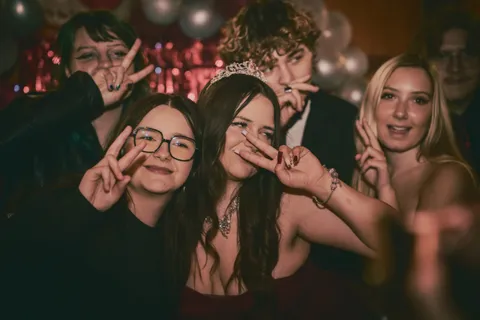 Jubilatka pozuje z grupą przyjaciół podczas imprezy urodzinowej.