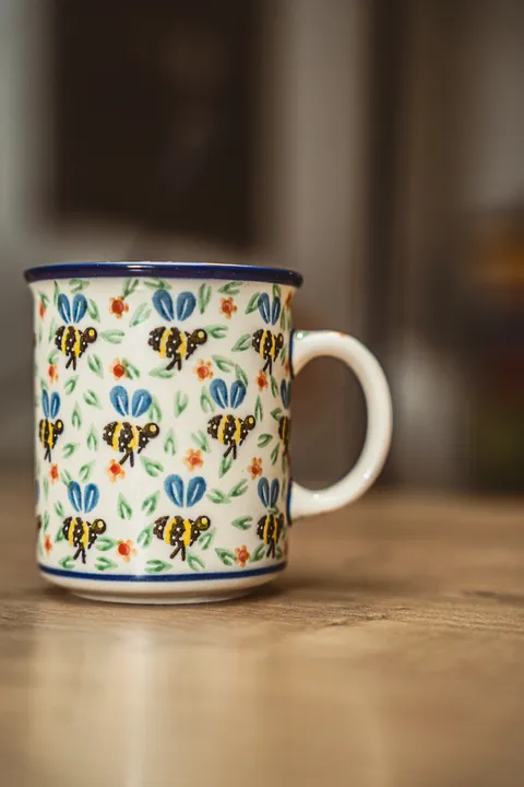 Ręcznie zdobiony kubek ceramiczny z motywem pszczół – fotografia produktowa